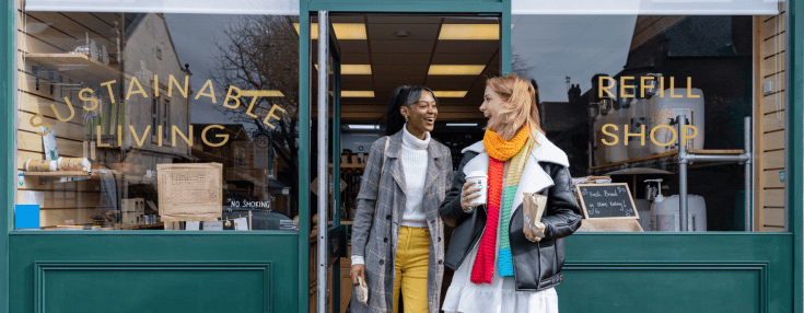 Interactive banner (SEP website) (735 x 286 px) Two women walking out of a refill shop with a sign that says 'sustainable living'