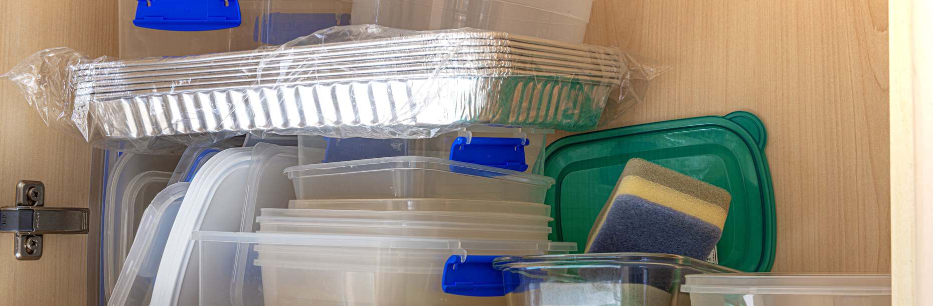 Reusable plastic food containers stacked in a kitchen cupboard